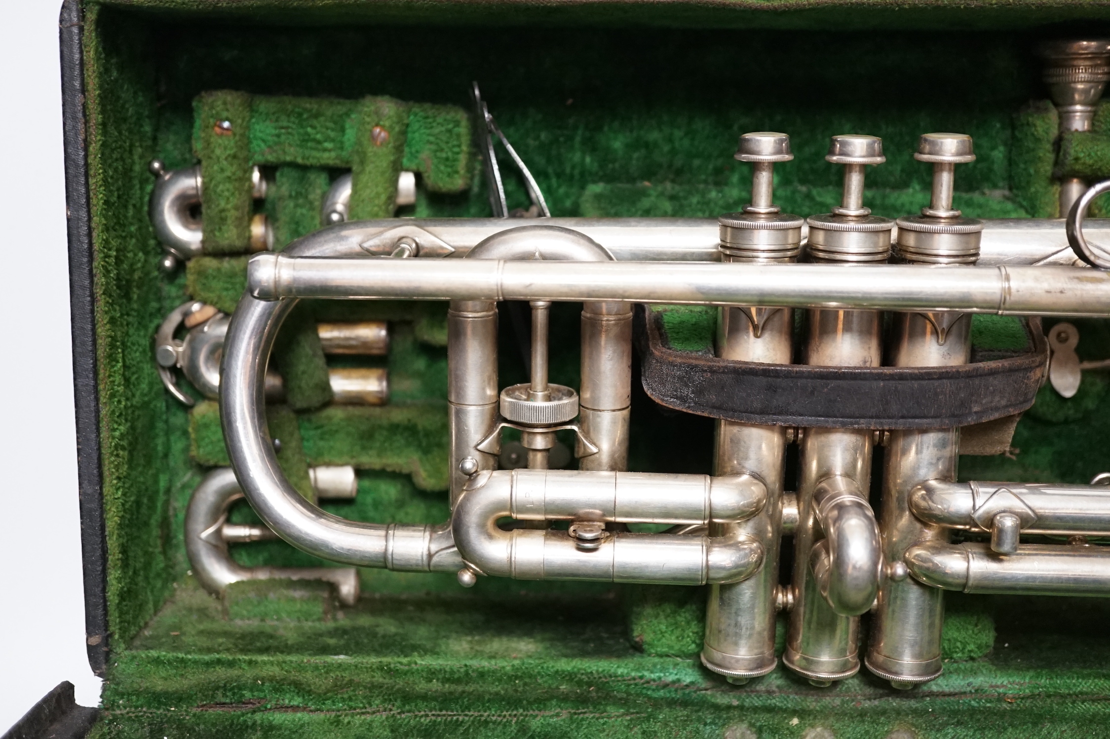 An Elkhart, Indiana No. 144989 trumpet, unusual trumpet with threaded fine adjust tuning slides, spare set of slides, two mouthpieces and two music lyres for marching, in a good fitted case, with a card boxed ‘maintenanc